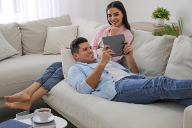 Couple with tablet resting on sofa in living room