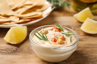 Delicious homemade hummus in glass bowl on wooden table
