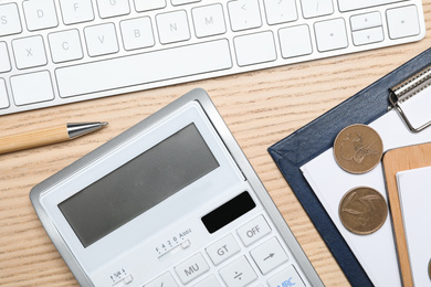 Calculator, money, keyboard and stationery on wooden table, flat lay. Tax accounting