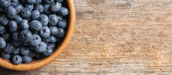 Tasty fresh blueberries on wooden table, top view with space for text. Banner design