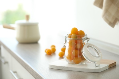 Pickling jar with fresh tomatoes on counter in kitchen. Space for text