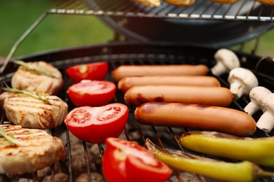 Photo of Barbecue grill with meat, sausages and vegetables outdoors, closeup
