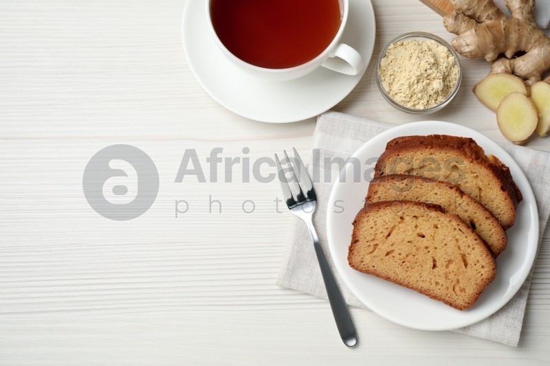 Photo of Slices of delicious gingerbread cake served with tea on white wooden table, flat lay. Space for text