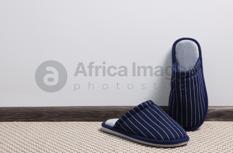 Photo of Pair of stylish slippers on carpet against light grey background, space for text