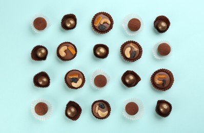 Photo of Different delicious chocolate candies on light blue background, flat lay