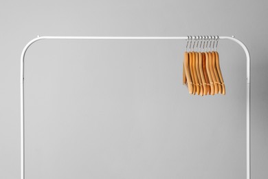 Photo of Wooden clothes hangers on metal rack against light grey background