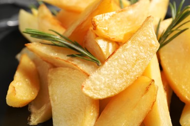 Photo of Tasty baked potato wedges and rosemary, closeup