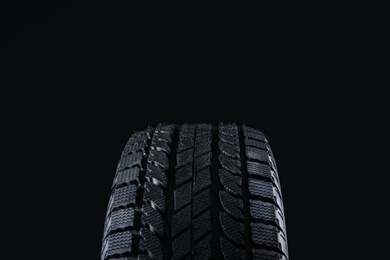 Winter tire on black background, closeup. Car maintenance