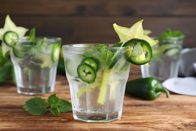 Photo of Spicy cocktail with jalapeno, carambola and mint on wooden table