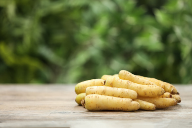Raw white carrots on wooden table against blurred background. Space for text