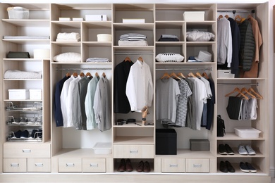 Photo of Stylish clothes, shoes and home stuff in large wardrobe closet
