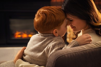 Photo of Happy mother and son hugging near fireplace at home