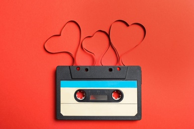 Music cassette and hearts made with tape on red background, top view. Listening love song