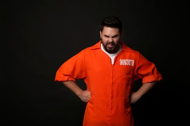Angry prisoner in jumpsuit on black background