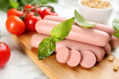 Fresh raw vegetarian sausages, soybeans and tomatoes on white marble table, closeup