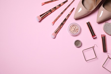 Makeup products, earrings and women's accessories on pink background, flat lay. Space for text