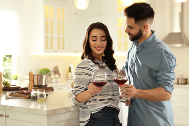Lovely young couple drinking wine while cooking together at kitchen