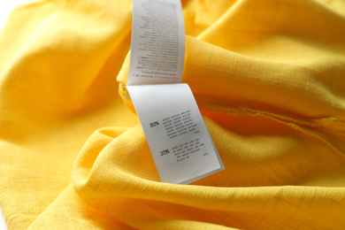 Clothing label with content information on yellow garment, closeup