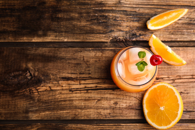 Fresh alcoholic Tequila Sunrise cocktail on wooden table, flat lay. Space for text