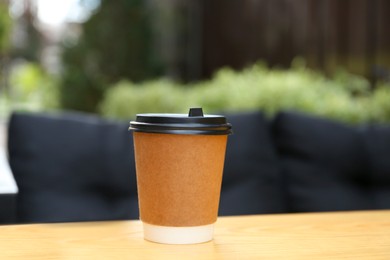 Photo of Paper cup on table in outdoor cafe. Coffee to go