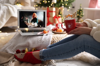 MYKOLAIV, UKRAINE - DECEMBER 25, 2020: Woman with sweet drink watching The Queen's Gambit series on laptop at home, closeup. Cozy winter holidays atmosphere