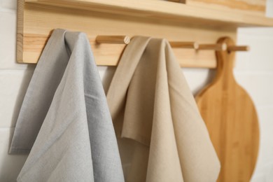 Different towels and wooden board hanging on rack in kitchen, closeup