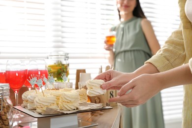 Woman taking delicious zephyr at baby shower party, closeup