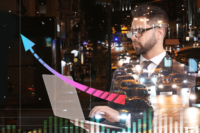 Double exposure of businessman with laptop and night cityscape. Stock exchange trading