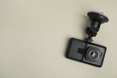 Modern car dashboard camera with suction mount on light background, top view. Space for text