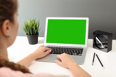Image of Woman using laptop at white desk, closeup. Device display with chroma key