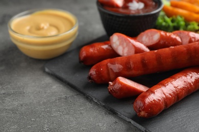 Delicious grilled sausages and vegetables on grey table, closeup. Space for text