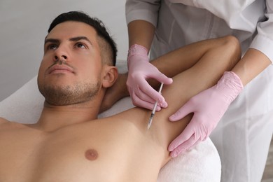 Cosmetologist injecting man's armpit in clinic. Treatment of hyperhidrosis