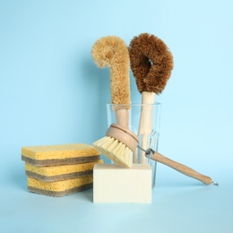 Cleaning supplies for dish washing on light blue background