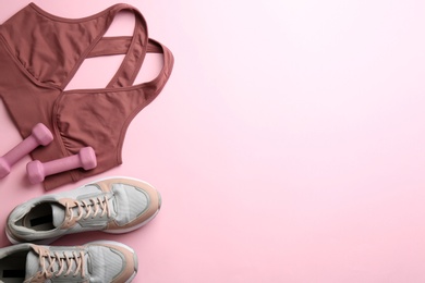 Sportswear and dumbbells on pink background, flat lay with space for text. Gym workout