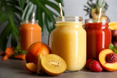 Delicious juices and fresh ingredients on grey table, closeup