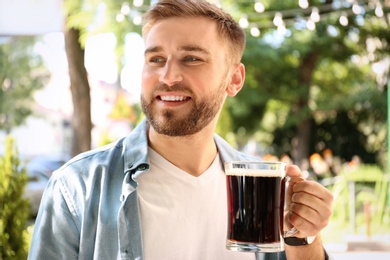 Handsome man with cold kvass outdoors. Traditional Russian summer drink