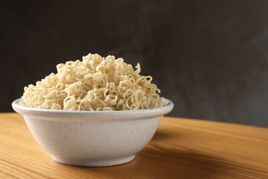 Photo of Bowl of hot noodles on table against grey background. Space for text
