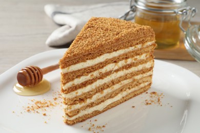 Photo of Slice of delicious layered honey cake served on plate, closeup