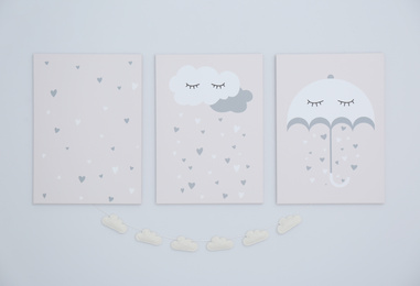 Cute posters and cloud garland on light wall. Interior elements