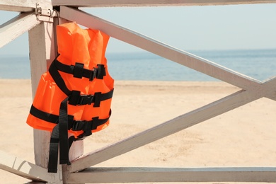 Orange life jacket hanging on wooden railing. Emergency rescue equipment