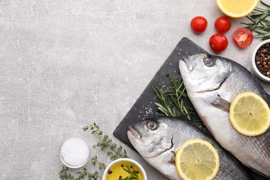 Photo of Flat lay composition with fresh raw dorado fish and ingredients on light grey table, space for text