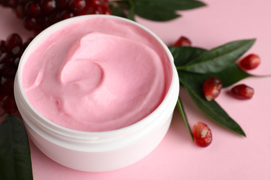 Fresh pomegranate and jar of facial mask on pink background, closeup. Natural organic cosmetics