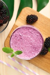 Delicious blackberry smoothie in glass and berries on wooden table, flat lay