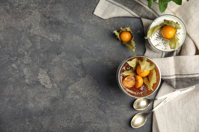 Delicious desserts decorated with physalis on grey table, flat lay. Space for text