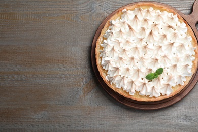 Delicious lemon meringue pie decorated with mint on wooden table, top view. Space for text