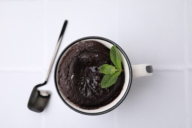 Photo of Tasty chocolate mug pie and spoon on white table, top view. Microwave cake recipe