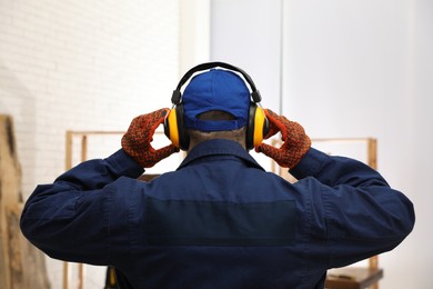Worker wearing safety headphones indoors, back view. Hearing protection device