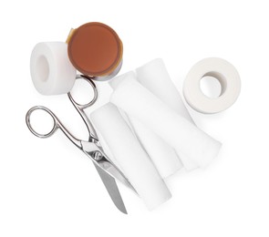 Medical bandage rolls, pills, sticking plaster and scissors on white background, top view