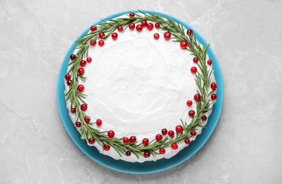 Traditional Christmas cake decorated with rosemary and cranberries on light grey marble table, top view