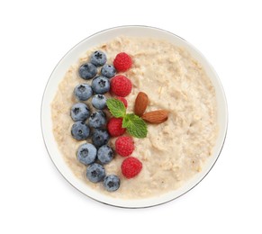 Tasty oatmeal porridge with raspberries, blueberries and almond nuts in bowl on white background, top view
